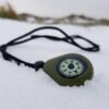 The CMP-20 Compass Necklace on snowy ground, with the oil-filled dial working perfectly as it won't freeze in sub-zero conditions.