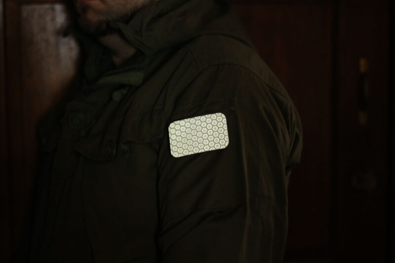 The glinting Cyflect Patch, attached to shoulder of a military jacket.